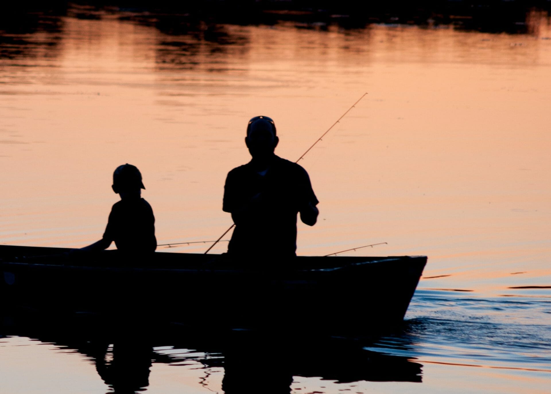 father and son fishing on a boat at sunrise